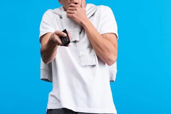 Cropped view of frightened man watching tv with remote controller, isolated on blue — Stock Photo