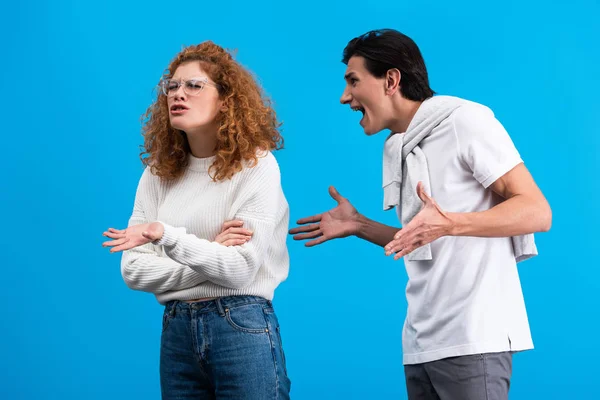 Fidanzato arrabbiato urlando fidanzata irritata, isolato su blu — Foto stock