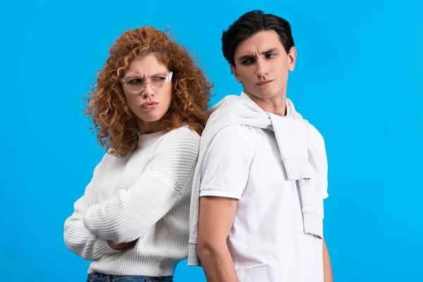 Irritated girlfriend and offended boyfriend standing back to back, isolated on blue — Stock Photo