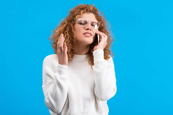 Müde Frau mit Brille, die auf dem Smartphone spricht, isoliert auf blauem Grund — Stockfoto