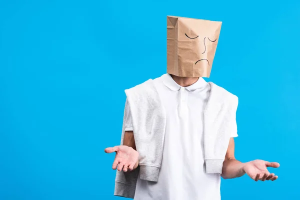 Hombre escéptico con triste bolsa de papel en la cabeza, aislado en azul - foto de stock