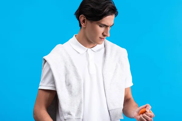 Angry young man squeezing stress ball, isolated on blue — Stock Photo