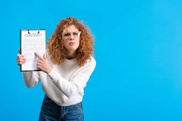 Irritated girl pointing at clipboard with contract, isolated on blue — Stock Photo