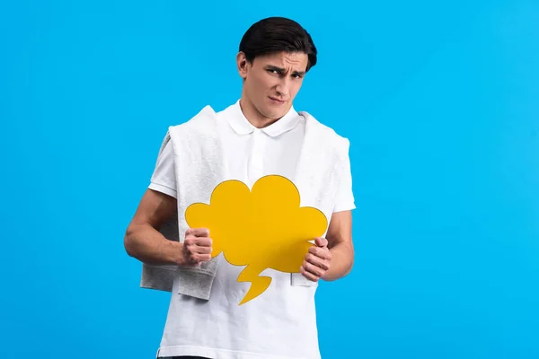 Confused man holding yellow cloud speech bubble, isolated on blue — Stock Photo