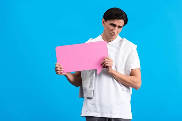 Upset man holding pink speech bubble, isolated on blue — Stock Photo