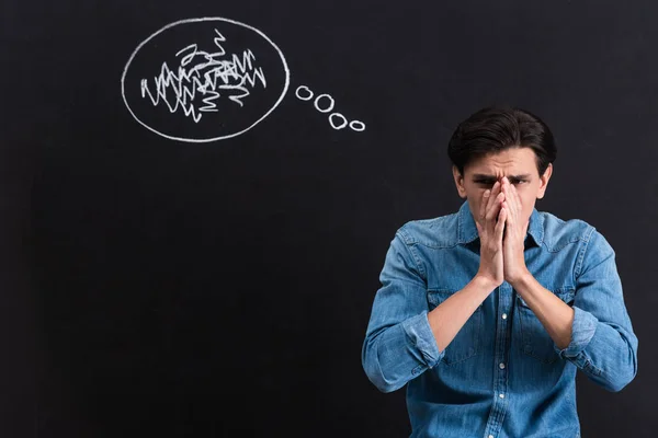 Frightened young man with thought bubble drawing on blackboard — Stock Photo