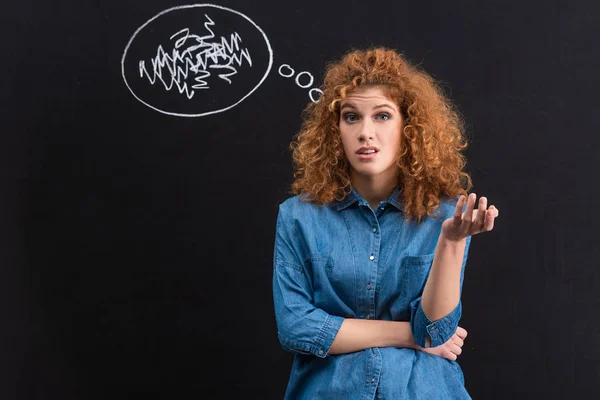 Pelirroja escéptica joven con burbuja de pensamiento en pizarra - foto de stock