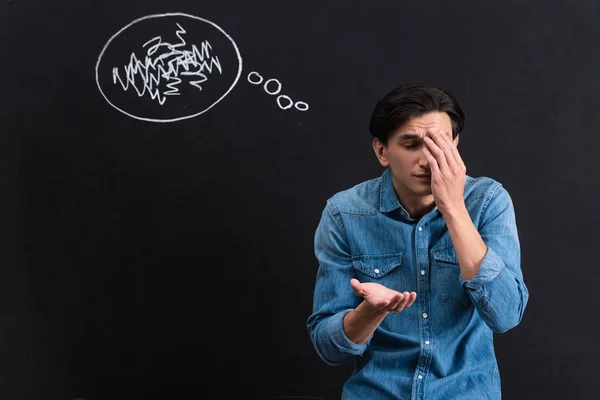 Confundido joven con el dibujo de la burbuja de pensamiento en pizarra - foto de stock