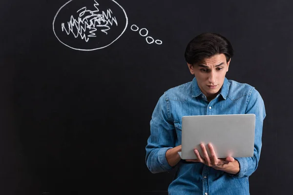 Homem emocional usando laptop, com vapor de orelhas desenhando no quadro negro — Fotografia de Stock