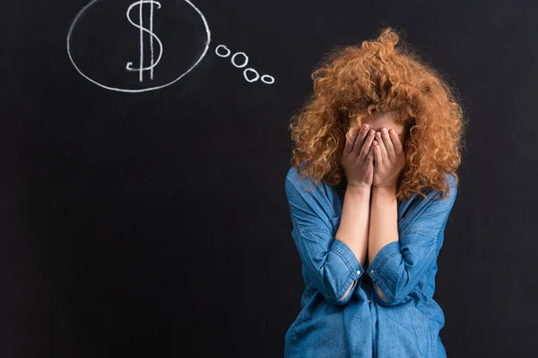 Frustrated girl with dollar sign in thought bubble on chalkboard — Stock Photo
