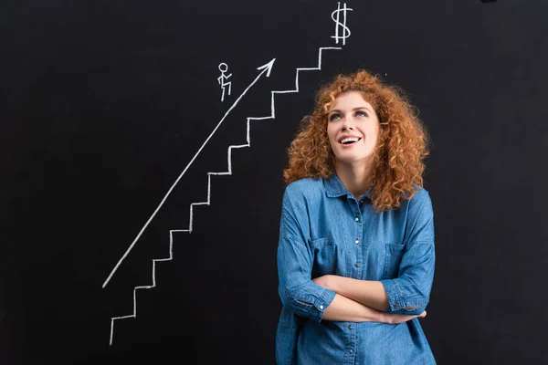 Ragazza rossa sorridente con braccia incrociate, start-up o crescita aziendale sulla lavagna — Foto stock