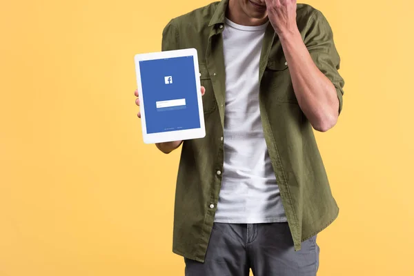 KYIV, UKRAINE - NOVEMBER 18, 2019: cropped view of man showing digital tablet with facebook app on screen, isolated on yellow — Stock Photo