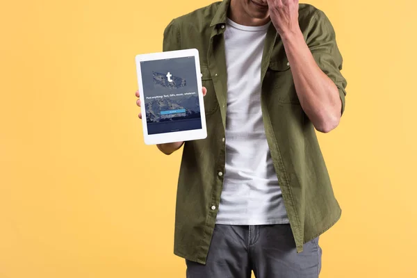 KYIV, UKRAINE - NOVEMBER 18, 2019: cropped view of man showing digital tablet with tumblr app on screen, isolated on yellow — Stock Photo