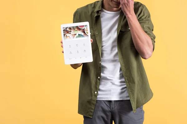 KYIV, UCRANIA - 18 de noviembre de 2019: vista recortada del hombre mostrando tableta digital con aplicación cuadrada en la pantalla, aislado en amarillo — Stock Photo