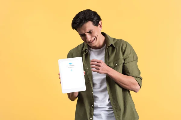 KYIV, UKRAINE - NOVEMBER 18, 2019: stressed man crying and showing digital tablet with skype app on screen, isolated on yellow — Stock Photo