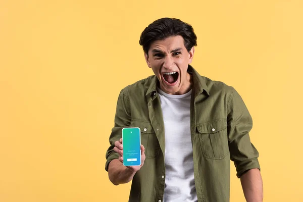 KYIV, UCRAINA - 18 NOVEMBRE 2019: uomo stressato che urla e mostra smartphone con app twitter sullo schermo, isolato su giallo — Foto stock