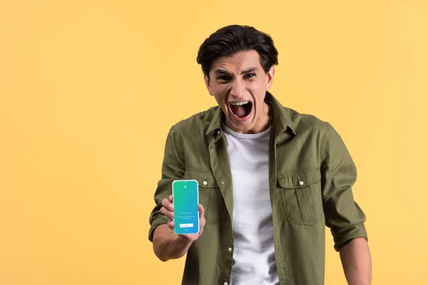 KYIV, UKRAINE - NOVEMBER 18, 2019: stressed man yelling and showing smartphone with twitter app on screen, isolated on yellow — Stock Photo