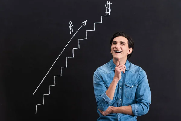 Alegre hombre pensativo con el dibujo de inicio en pizarra - foto de stock