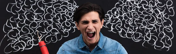 Panoramic shot of aggressive young man yelling and holding dynamite sticks, with steam drawing on blackboard — Stock Photo