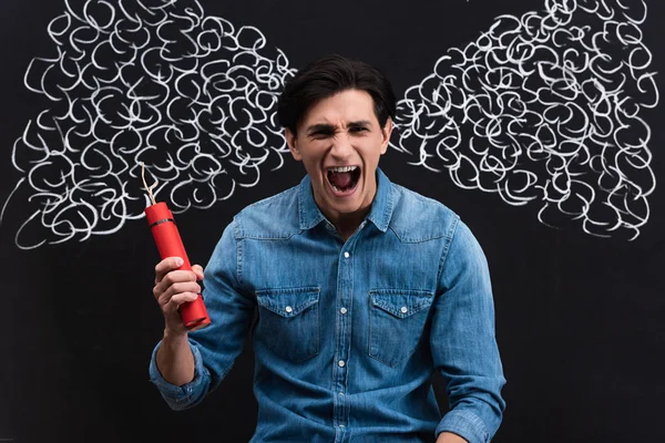 Angry young man shouting and holding dynamite, with steam drawing on blackboard — Stock Photo