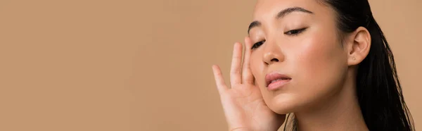 Hermosa chica asiática tocando cara aislado en beige, tiro panorámico - foto de stock