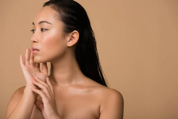 Beautiful naked asian girl  looking away and touching face isolated on beige — Stock Photo