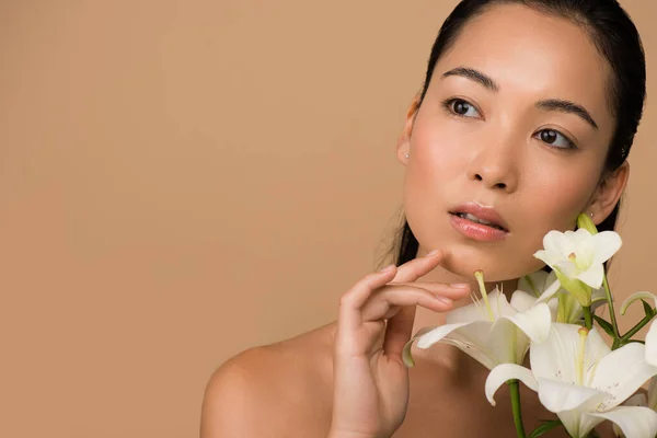 Dreamy beautiful naked asian girl with white lilies isolated on beige — Stock Photo