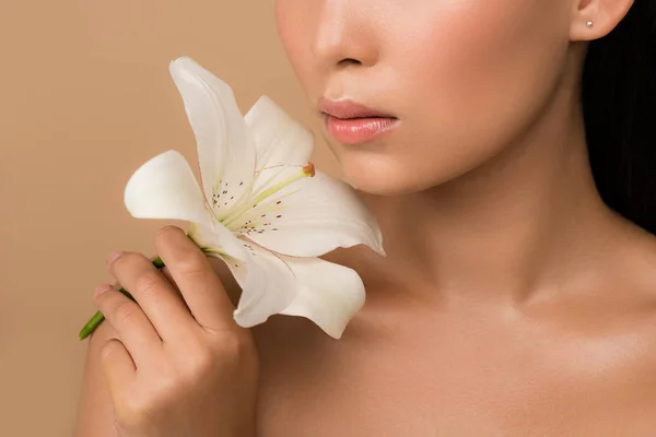 Recortado vista de hermosa desnuda chica asiática sosteniendo lirio blanco aislado en beige - foto de stock