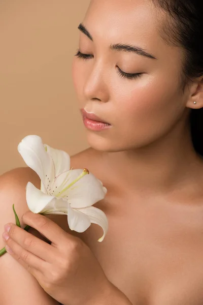 Beautiful naked asian girl holding white lily isolated on beige — Stock Photo