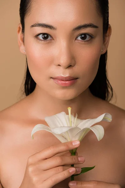 Beautiful naked asian girl holding white lily isolated on beige — Stock Photo