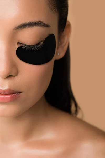 Recadrée vue de belle nu asiatique fille avec noir hydrogel oeil patch sous fermé oeil isolé sur beige — Photo de stock