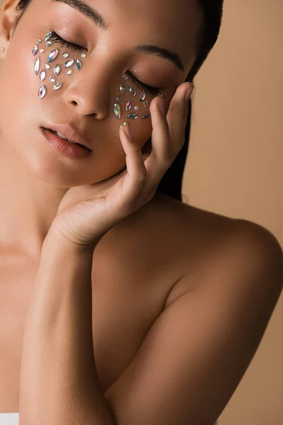 Beautiful naked asian girl with closed eyes and rhinestones on face isolated on beige — Stock Photo