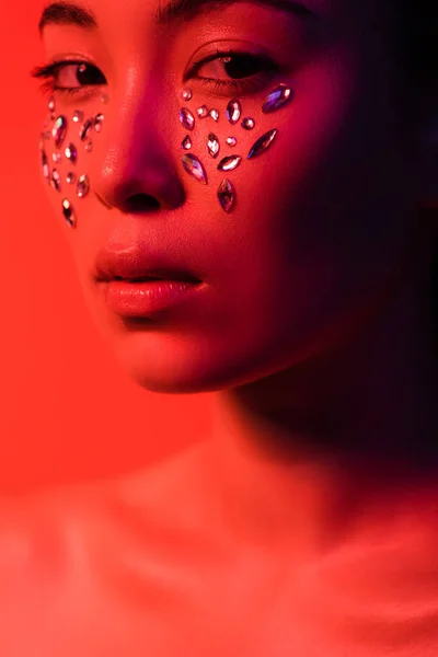 Beautiful naked asian girl with rhinestones on face isolated on red — Stock Photo