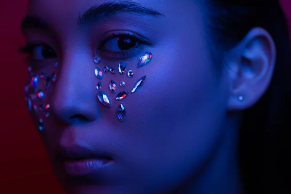 Beautiful asian girl with rhinestones on face in blue light — Stock Photo