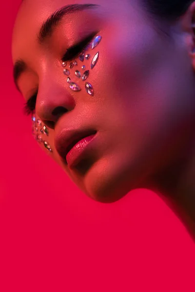 Beautiful asian girl with rhinestones on face isolated on red — Stock Photo