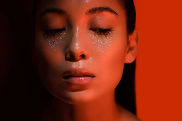 Belle asiatique fille avec argent scintille sur visage sur rouge et noir — Photo de stock