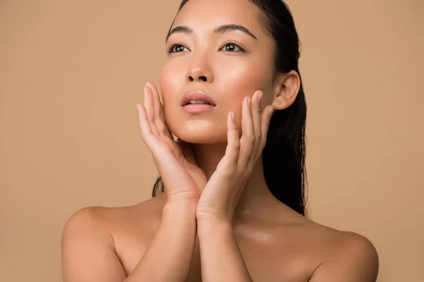 Schöne nackte asiatische Mädchen Gesicht berühren und wegschauen isoliert auf beige — Stockfoto