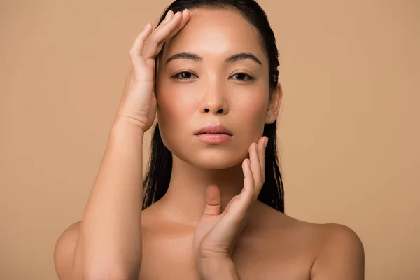 Beautiful naked asian girl touching face isolated on beige — Stock Photo