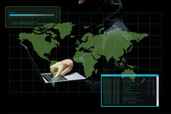 Vista recortada de hacker en la capucha usando el ordenador portátil cerca del mapa del mundo en negro - foto de stock