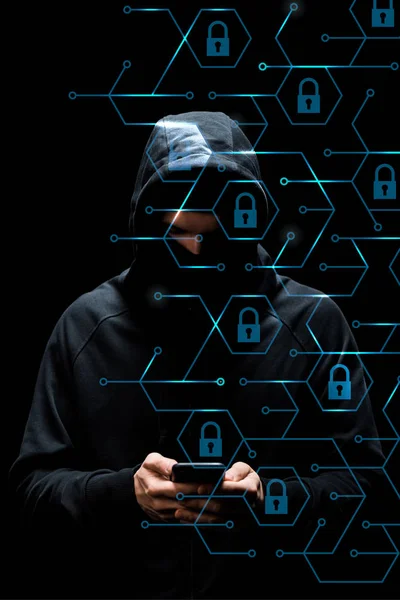 Hacker no capuz usando smartphone perto de cadeados em preto, conceito de segurança cibernética — Fotografia de Stock