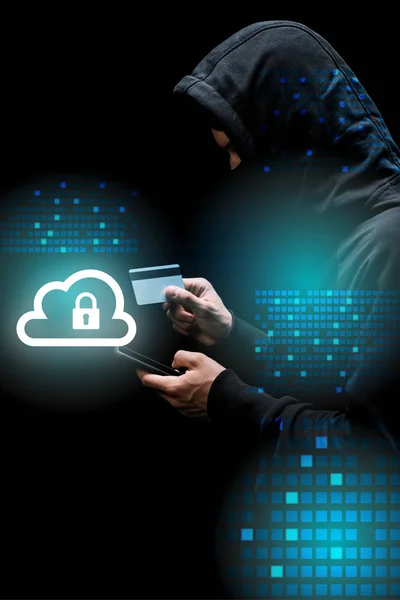 Hacker in hood and mask using smartphone and holding credit card near cloud with padlock illustration on black — Stock Photo