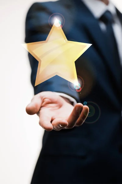 Cropped view of businessman in suit with outstretched hand near star on white, quality concept — Stock Photo