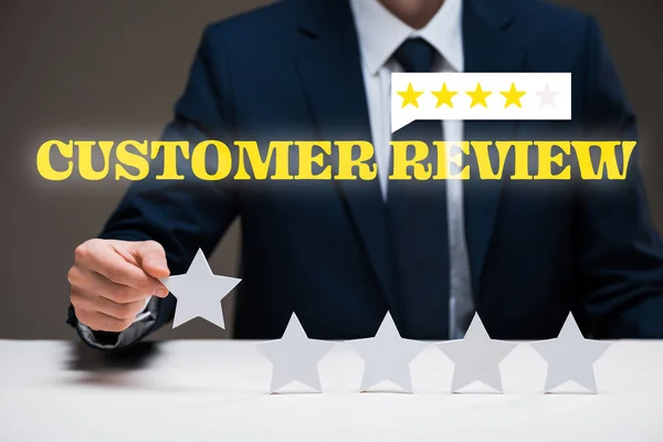 Cropped view of businessman holding star near customer review lettering on grey, quality concept — Stock Photo