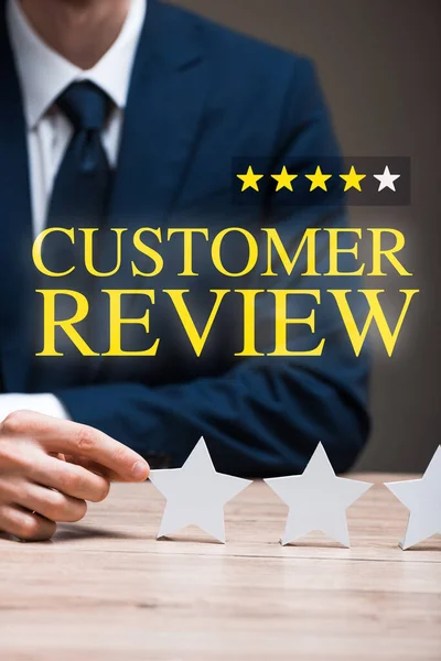 Cropped view of man in formal wear touching star near customer review lettering on grey, quality concept — Stock Photo