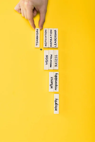 Vista superior del hombre sosteniendo un bloque de madera con letras de trabajo en equipo aisladas en amarillo - foto de stock