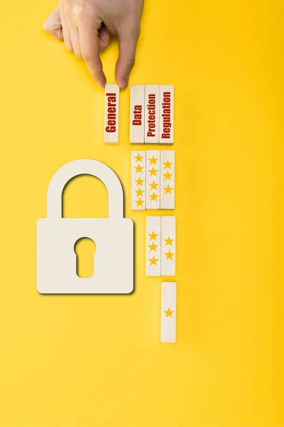 Top view of man holding wooden block with general lettering near padlock on yellow — Stock Photo