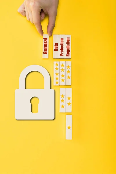 Vista superior del hombre sosteniendo el bloque de madera con letras generales cerca del candado en amarillo - foto de stock