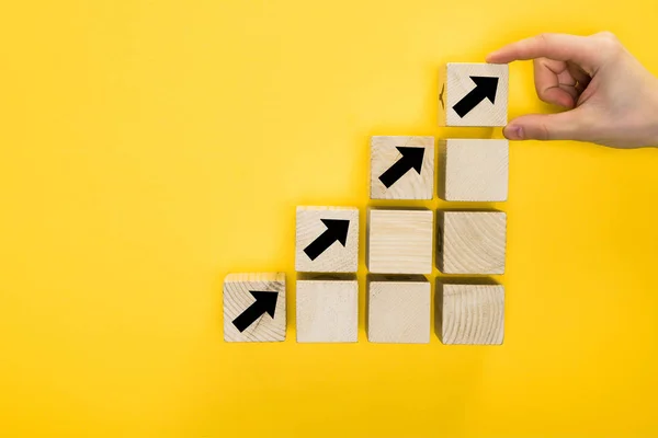 Vue de dessus du cube homme tenant avec flèche directionnelle isolé sur jaune, concept de qualité — Photo de stock