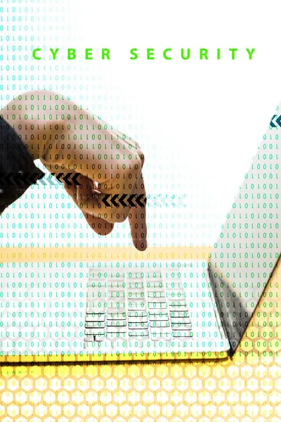 Vista recortada de hacker apuntando con el dedo a la computadora portátil cerca de letras de seguridad cibernética en blanco - foto de stock