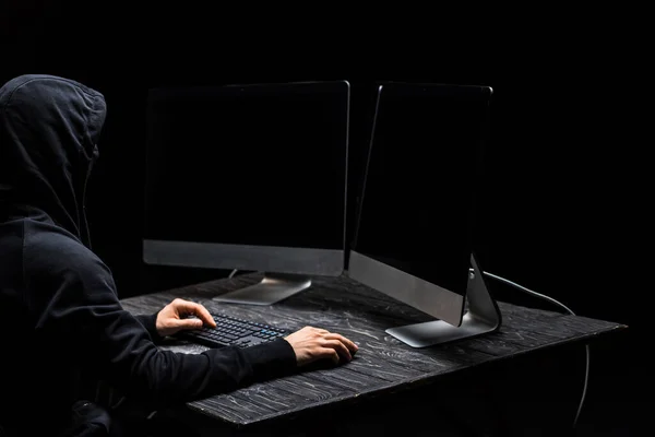 Hacker using computer mouse and looking at computer monitors with blank screen isolated on black — Stock Photo